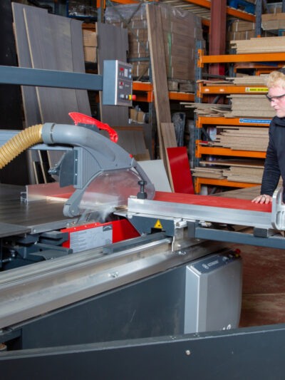 A photo of a woodworking machinery operator cutting wood on a panel saw